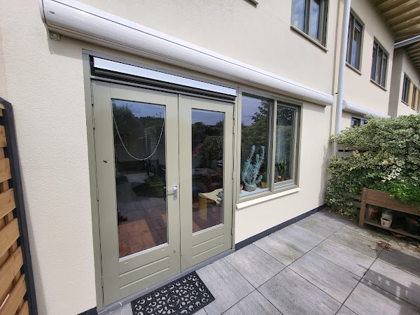 Openslaande tuindeuren in een zachtgroene tint met terras.